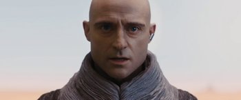 Movie still from “John Carter” (2012), directed by Andrew Stanton – A bald man wearing a gray scarf and ear buds; Close Up shot, Low angle