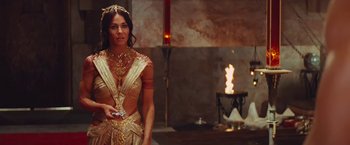 Movie still from “John Carter” (2012), directed by Andrew Stanton – A beautiful woman in a gold dress holding a cell phone; Medium shot, Over the shoulder angle