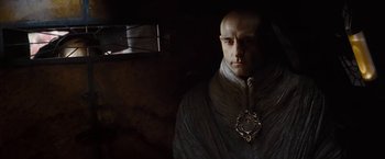 Movie still from “John Carter” (2012), directed by Andrew Stanton – A bald man with a beard wearing a suit; Medium shot, Over the shoulder angle