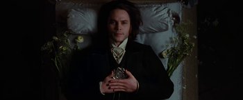 Movie still from “John Carter” (2012), directed by Andrew Stanton – A man laying in a bed holding an alarm clock in his hands; Medium shot, Overhead angle