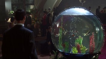 Movie still from “Johnny Mnemonic” (1995), directed by Robert Longo – A group of people in a room looking at a fish tank; Wide shot, High angle