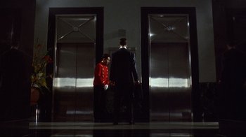 Movie still from “Johnny Mnemonic” (1995), directed by Robert Longo – A man and a woman standing next to each other in front of two elevators; Wide shot, Low angle