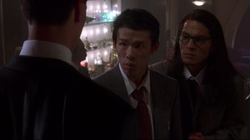 Movie still from “Johnny Mnemonic” (1995), directed by Robert Longo – A group of people standing next to each other in a room; Medium shot, Over the shoulder angle