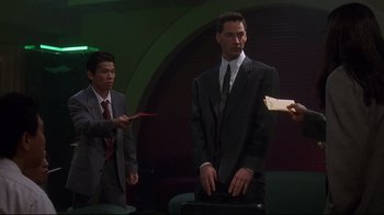 Movie still from “Johnny Mnemonic” (1995), directed by Robert Longo – A man in a suit and tie holding a piece of paper; Medium shot, Low angle