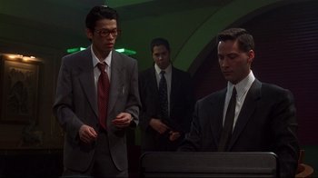 Movie still from “Johnny Mnemonic” (1995), directed by Robert Longo – A group of men standing next to each other in a room; Medium shot, Low angle