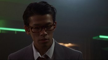 Movie still from “Johnny Mnemonic” (1995), directed by Robert Longo – A man in a suit and tie looking down; Close Up shot, Low angle