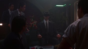 Movie still from “Johnny Mnemonic” (1995), directed by Robert Longo – A group of people sitting around a table; Medium shot, Over the shoulder angle
