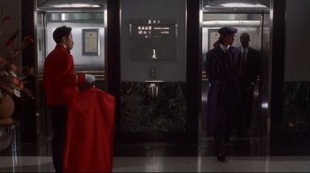 Movie still from “Johnny Mnemonic” (1995), directed by Robert Longo – Two men in red and purple coats are standing in front of urinals; Wide shot, Low angle