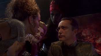 Movie still from “Johnny Mnemonic” (1995), directed by Robert Longo – A group of people standing next to each other in a dark room; Close Up shot, Over the shoulder angle