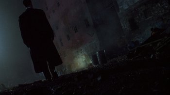 Movie still from “Johnny Mnemonic” (1995), directed by Robert Longo – A person standing in the dark near a building; Wide shot, Low angle