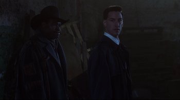 Movie still from “Johnny Mnemonic” (1995), directed by Robert Longo – Two men standing next to each other in the dark; Medium shot, Low angle