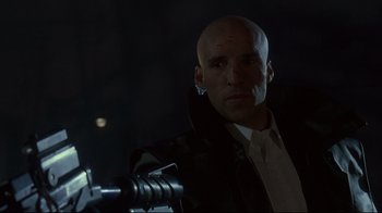 Movie still from “Johnny Mnemonic” (1995), directed by Robert Longo – A bald man in a black jacket is looking at the camera; Close Up shot, Low angle