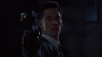 Movie still from “Johnny Mnemonic” (1995), directed by Robert Longo – A man holding a gun up to his face; Close Up shot, Low angle