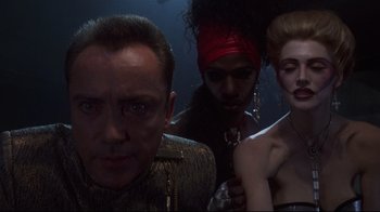 Movie still from “Johnny Mnemonic” (1995), directed by Robert Longo – A man and two women standing next to each other; Close Up shot, Low angle