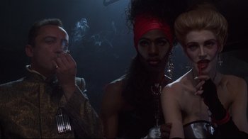 Movie still from “Johnny Mnemonic” (1995), directed by Robert Longo – A group of people standing next to each other in a dark room; Close Up shot, Over the shoulder angle