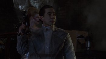 Movie still from “Johnny Mnemonic” (1995), directed by Robert Longo – A man holding a gun while standing next to a woman; Medium shot, Low angle