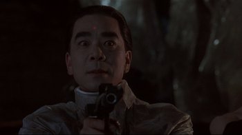 Movie still from “Johnny Mnemonic” (1995), directed by Robert Longo – A man holding a camera in a dark room; Close Up shot, Low angle