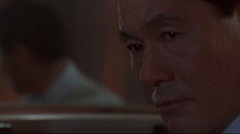 Movie still from “Johnny Mnemonic” (1995), directed by Robert Longo – A man's face in a dimly - lit room; Close Up shot, Over the shoulder angle