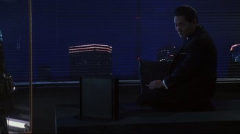 Movie still from “Johnny Mnemonic” (1995), directed by Robert Longo – A man sitting on the ground using a laptop computer; Medium shot, Over the shoulder angle