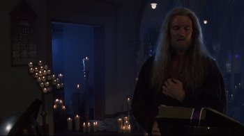 Movie still from “Johnny Mnemonic” (1995), directed by Robert Longo – A man with long white hair standing in front of candles in a room; Medium shot, Low angle