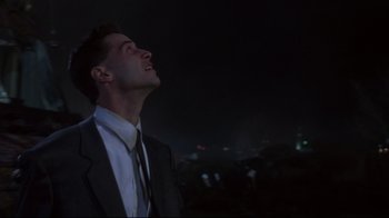 Movie still from “Johnny Mnemonic” (1995), directed by Robert Longo – A man in a suit and tie looking up at the sky; Close Up shot, Low angle
