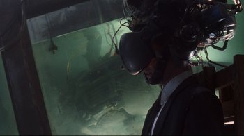 Movie still from “Johnny Mnemonic” (1995), directed by Robert Longo – A man wearing a suit and wearing a virtual reality headset in front of an aquarium; Medium shot, High angle