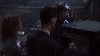 Movie still from “Johnny Mnemonic” (1995), directed by Robert Longo – Two men are standing in a dark room looking at a video screen; Medium shot, Over the shoulder angle