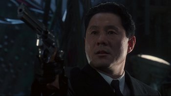 Movie still from “Johnny Mnemonic” (1995), directed by Robert Longo – A person holding a gun; Close Up shot, Low angle