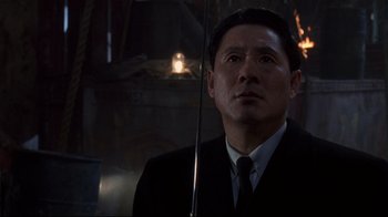 Movie still from “Johnny Mnemonic” (1995), directed by Robert Longo – A man wearing a suit and tie holding a cane; Close Up shot, Low angle