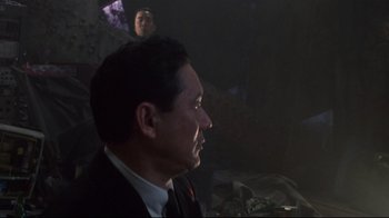 Movie still from “Johnny Mnemonic” (1995), directed by Robert Longo – A person wearing a suit and tie; Medium shot, Over the shoulder angle