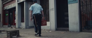 Movie still from “Judas and the Black Messiah” (2021), directed by Shaka King – A police officer walking down the street with a bag; Wide shot, High angle