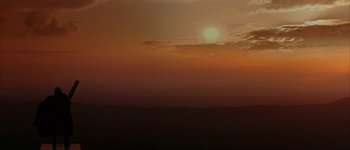 Movie still from “Judge Dredd” (1995), directed by Danny Cannon – The sun is setting over the ocean on a cloudy day; Extreme Wide shot, Low angle