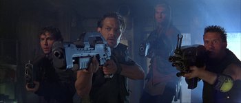 Movie still from “Judge Dredd” (1995), directed by Danny Cannon – A man holding a gun while standing next to another man; Medium shot, Low angle