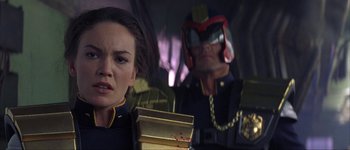 Movie still from “Judge Dredd” (1995), directed by Danny Cannon – A woman and a man wearing a helmet and holding a box; Close Up shot, Low angle