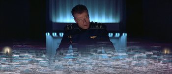 Movie still from “Judge Dredd” (1995), directed by Danny Cannon – A man in a uniform sitting in front of water; Medium shot, High angle