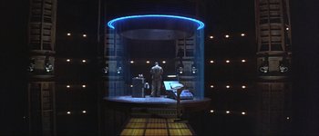 Movie still from “Judge Dredd” (1995), directed by Danny Cannon – A man standing on a stage in front of lights; Extreme Wide shot, High angle