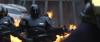 Movie still from “Judge Dredd” (1995), directed by Danny Cannon – A man in a suit and helmet is holding a gun; Medium shot, Low angle