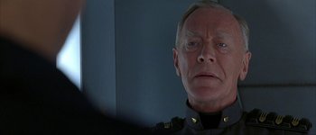 Movie still from “Judge Dredd” (1995), directed by Danny Cannon – An older man wearing a uniform looking at the camera; Close Up shot, Over the shoulder angle