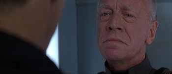 Movie still from “Judge Dredd” (1995), directed by Danny Cannon – An older man looking into a mirror in a room; Close Up shot, Over the shoulder angle