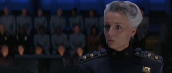 Movie still from “Judge Dredd” (1995), directed by Danny Cannon – An older woman is looking at the camera while people watch; Close Up shot, Low angle