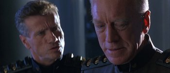 Movie still from “Judge Dredd” (1995), directed by Danny Cannon – A man in a military uniform looking down at another man in a military uniform; Close Up shot, Over the shoulder angle