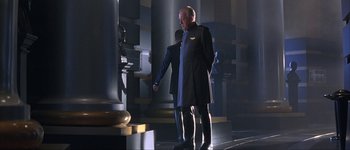 Movie still from “Judge Dredd” (1995), directed by Danny Cannon – A man in a suit and tie standing next to another man in a suit and tie; Wide shot, Low angle