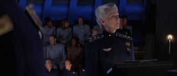 Movie still from “Judge Dredd” (1995), directed by Danny Cannon – An older woman in a uniform stands in front of a group of people; Close Up shot, Low angle
