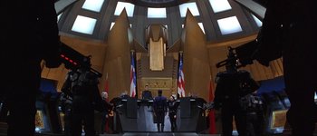 Movie still from “Judge Dredd” (1995), directed by Danny Cannon – A group of men standing in front of a stage; Extreme Wide shot, High angle