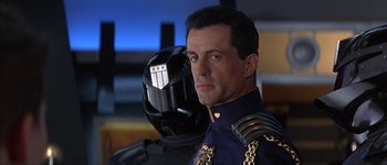 Movie still from “Judge Dredd” (1995), directed by Danny Cannon – A person wearing a uniform and a helmet; Close Up shot, Low angle