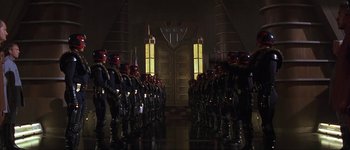 Movie still from “Judge Dredd” (1995), directed by Danny Cannon – A group of men in uniform standing next to each other in front of a door; Extreme Wide shot, Low angle