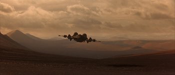 Movie still from “Judge Dredd” (1995), directed by Danny Cannon – A fighter jet flying through the air on top of a hill; Extreme Wide shot, Low angle