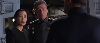 Movie still from “Judge Dredd” (1995), directed by Danny Cannon – A man in a uniform talking to another man in a suit; Close Up shot, Over the shoulder angle