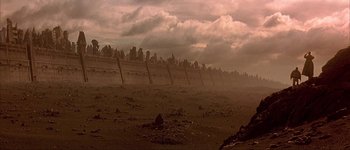 Movie still from “Judge Dredd” (1995), directed by Danny Cannon – A very long fence in the middle of a field; Extreme Wide shot, Low angle