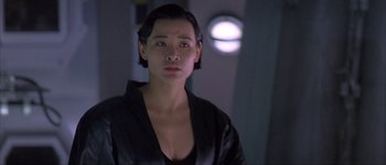 Movie still from “Judge Dredd” (1995), directed by Danny Cannon – A woman in a leather jacket looking at the camera; Close Up shot, Over the shoulder angle